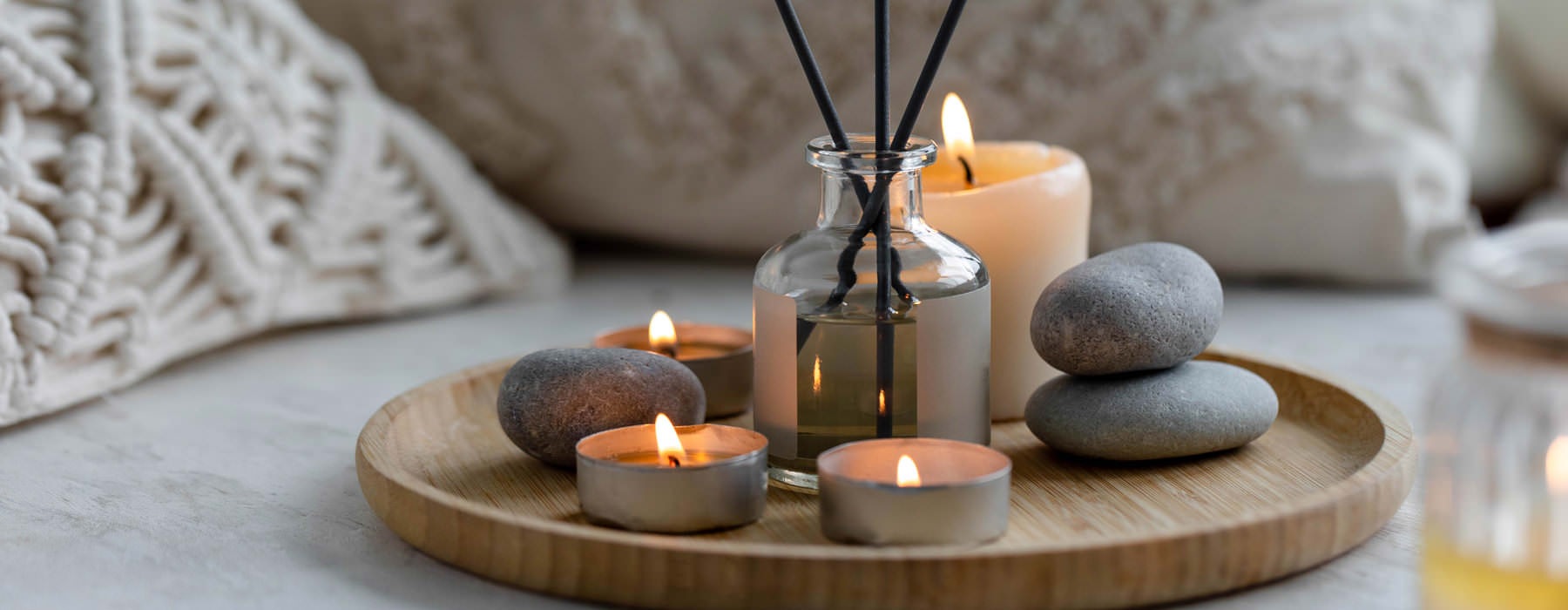 candles, stones and infused reeds on a wooden plate 